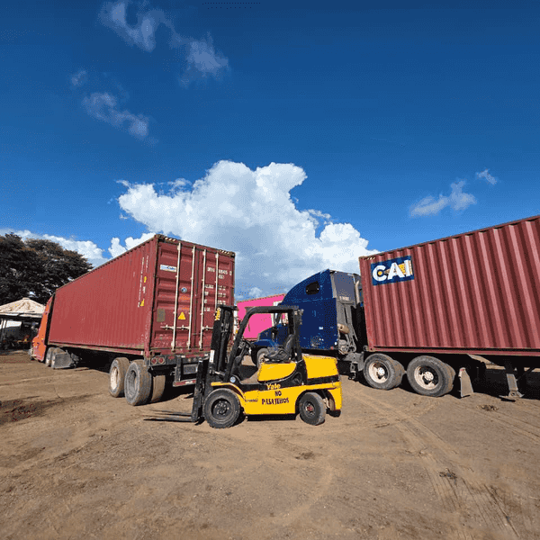 Montacargas amarillo cargando contenedores de carga sobre un trailer en un patio de maniobra