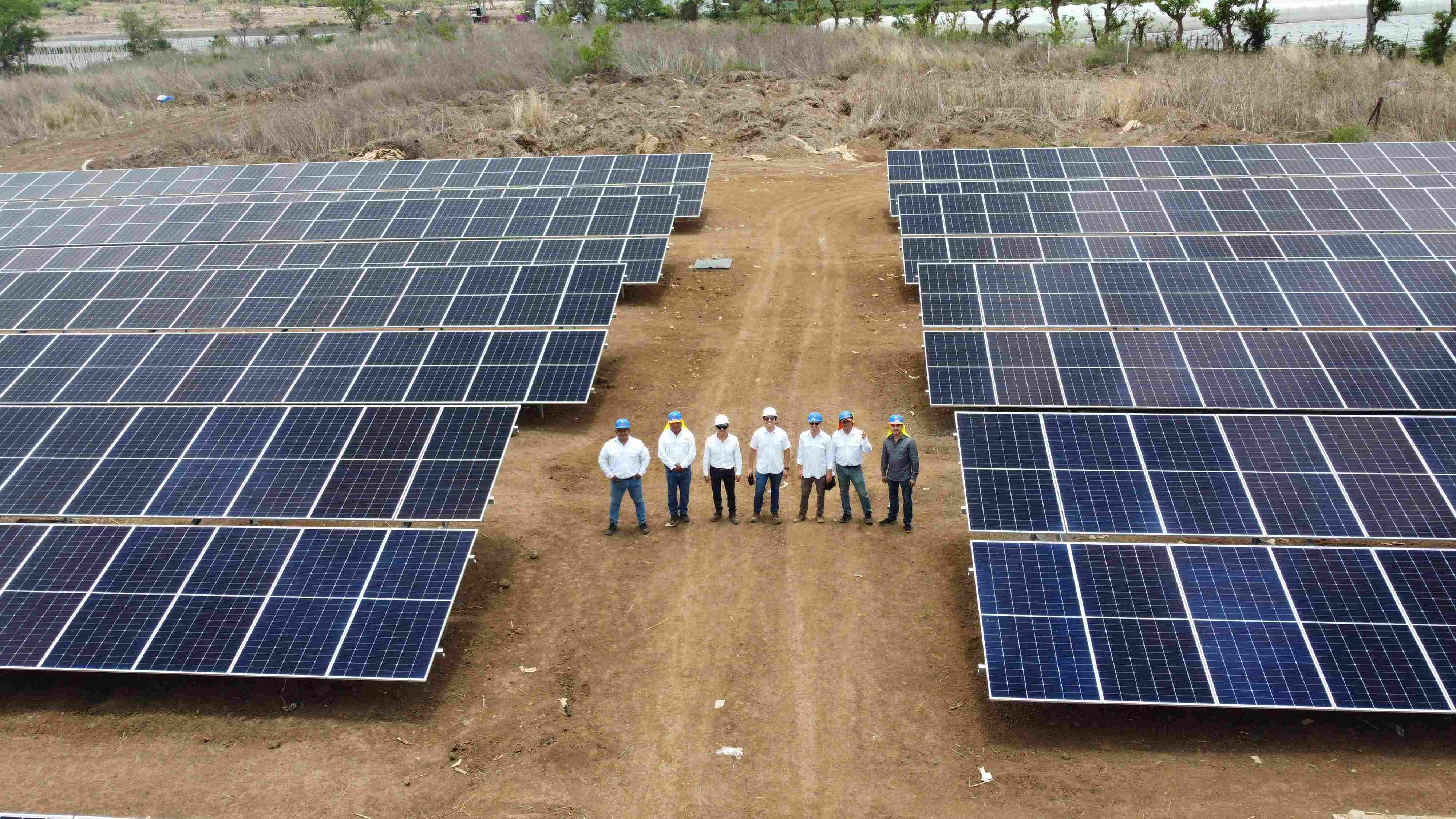 Equipo de ingenieros e instaladores del Parque Solar Jutiapa posando entre filas de paneles solares